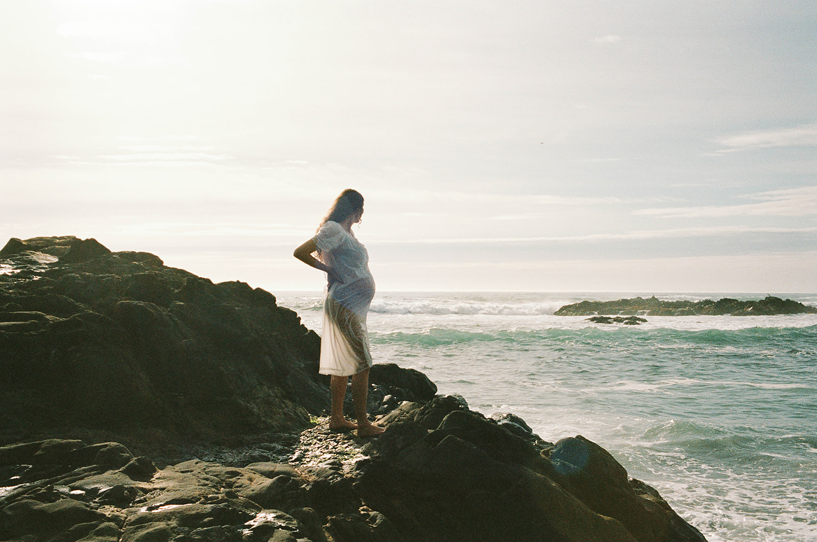 pregnant woman on rocks on seaside